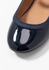 Granatowe lakierowane baleriny z błyszczącym granatowym tekstylnym wykończeniem wokół otwarcia i gładką, połyskującą czubkiem.