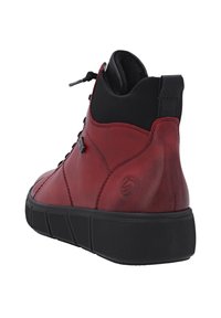 Bottine en cuir rouge avec des accents noirs, bout arrondi et semelle en caoutchouc texturé. Dotée d'un design à lacets et d'un talon renforcé.