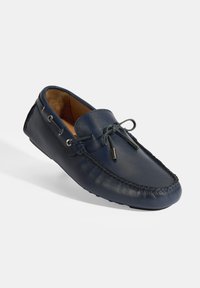 Marineblauwe leren instappers met een ronde neus, gedetailleerde stiksels, veteraccenten en een soepele textuur. Het interieur is voorzien van een zachte tan voering.