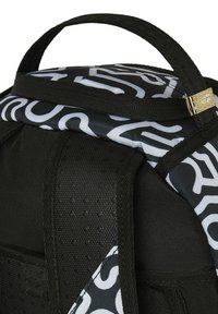 Mochila negra con un asa superior, tejido texturizado, patrón abstracto blanco y detalle de hardware dorado en la correa.