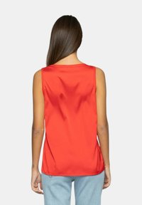 Top senza maniche in satin rosso con vestibilità morbida, caratterizzato da una texture liscia e una leggera lucentezza. La vista da dietro mostra linee pulite e nessun abbellimento.