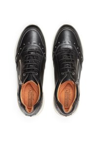 Zapatillas de cuero negro con cordones y cremalleras laterales, detalles de tachuelas metálicas, plantillas color canela y suelas de goma blanca, vistas desde arriba sobre un fondo blanco.