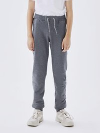 Grå joggebukser med elastisk midje og snøring. Har sidelommer, smalner inn mot leggen og ribbestrikkede ankler. Brukt med beige joggesko.