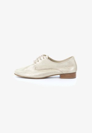 Chaussure Oxford en cuir beige avec petit talon en bois et lacets, vue de profil sur fond blanc.