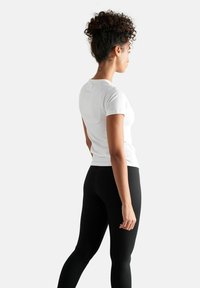 Witte t-shirt met korte mouwen en een ronde halslijn, gecombineerd met zwarte leggings. Glad materiaal, aansluitend ontwerp en een eenvoudige silhouette.