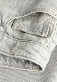Μανίκι ανοιχτό γκρι τζιν μπουφάν με ραμμένο μανσέτα και μικρή τσέπη, στερεωμένη με μεταλλικά καρφιά σε υφή ύφασμα.