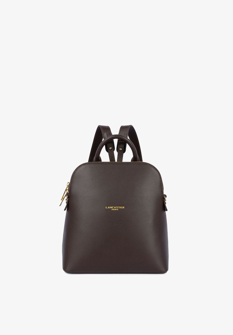 Sac à dos en cuir marron foncé Lancaster Paris avec fermeture éclair dorée, bretelles réglables et poignée supérieure sur fond blanc.