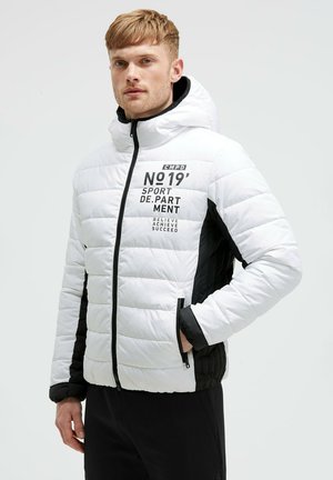 Weiß-schwarze Daunenjacke mit Reißverschluss. Verfügt über Textgrafiken auf der Vorderseite und eine Kapuze. Gequiltete Textur und seitliche Taschen.
