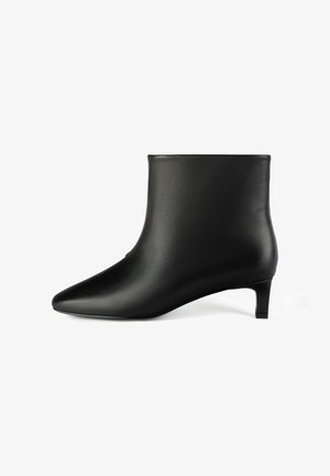 Fekete bőrből készült bokacsizma hegyes orral és 2 hüvelykes kúp talppal. Simaság jellemzi és zökkenőmentes dizájn, magas szárú, látható záródások nélkül.