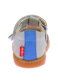 Sandalia gris con un acento azul, asegurada por una correa, con una suela de goma. Etiqueta del logo de Kickers visible en el costado. Forro interior suave.