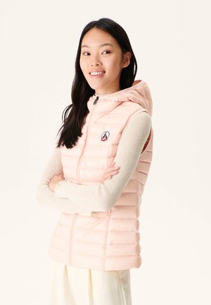 Light pink padded vest with a hood, featuring a front zip closure, ribbed sleeves, and a logo patch on the chest. Soft texture and quilted pattern.