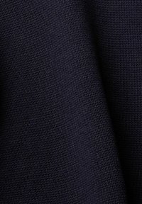 Tissu en tricot bleu marine foncé avec un motif de point serré et uniforme, présentant de légers plis créant des ombres douces.