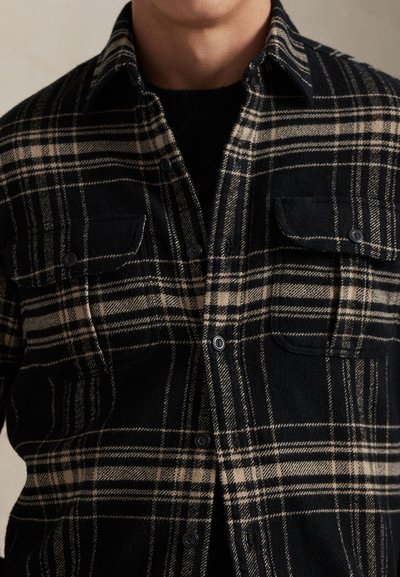 Μαύρο και καφέ καρό φλις πουκάμισο με κουμπωτό μπροστινό μέρος, δύο τσέπες στο στήθος και απαλής υφής, διαθέτει γιακά και κουμπιά σε αντίθεση.