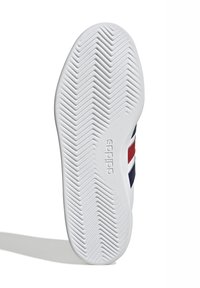 Bijela guma tenisice s herringbone uzorkom za prianjanje. Sadrži crvene i mornarsko plave pruge uz bocu, utisnuti logo blizu pete.