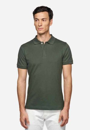 Polo de algodón verde oscuro con cuello clásico, tapeta de dos botones, mangas cortas y una textura suave. Sin patrones ni acentos visibles.