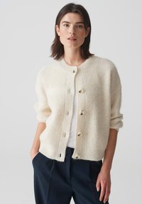 Cremefarbener Cardigan mit strukturiertem Strickmuster, runder Ausschnitt, Knopfverschluss und Dreiviertelärmel.