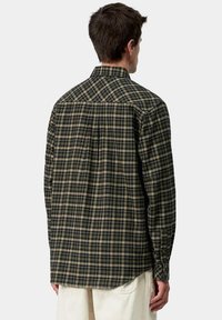 Camisa a cuadros en verde y beige con yugo trasero, puños con botón y dobladillo curvado. Fabricada con un tejido ligero de acabado texturizado.