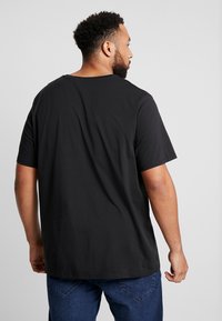 Zwarte T-shirt met korte mouwen en een ronde hals, gemaakt van zacht materiaal. Heeft een losse pasvorm en een minimaal ontwerp zonder zichtbare logo's of patronen.