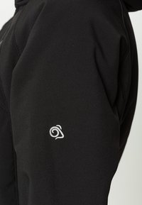 Schwarze Jacke mit einer eleganten, glatten Textur und einem sichtbaren Logo auf dem linken Ärmel. Die Stickdetails betonen das Design.