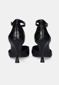 Sandalias de tacón alto negras con acabado brillante, textura de cocodrilo, correa en el tobillo y un tacón de aguja delgado. Diseño de espalda abierta.