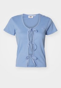 Tricou ribbed de culoare albastră deschisă, cu mâneci scurte, având un decolteu adânc în formă de V și legături în față pentru ajustare. Numele brandului este brodat pe piept.