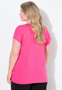 Růžový krátký rukáv top vyrobený z měkké bavlny. Má uvolněný střih s kulatým lemem, doplněný hladkým povrchem.