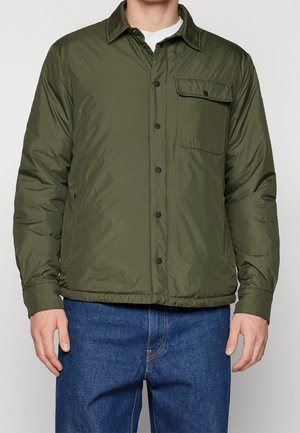 Veste matelassée olive avec fermoir à boutons sur le devant, col, poche poitrine et poches latérales ; fabriquée en tissu lisse et léger.