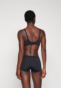 Black bra and matching shorts made of smooth fabric. Bra features adjustable straps and a hook closure at the back. Simple design.