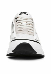 Zapatilla deportiva blanca con acentos negros, que presenta una parte superior de malla, suela gruesa y punta redonda. Los cordones en fila cubren la parte delantera.