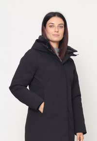 Cappotto nero imbottito con cappuccio, caratterizzato da una texture liscia, maniche lunghe e tasche laterali. Chiusura frontale con zip.