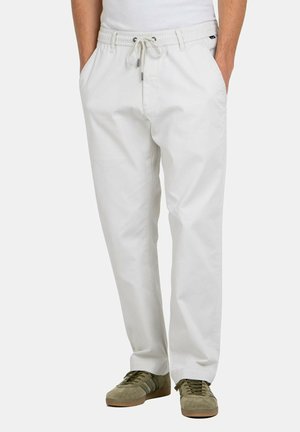 White, relaxed-fit pants with an elastic waistband and drawstring. Soft fabric, side pockets, and a smooth finish. Paired with green sneakers.