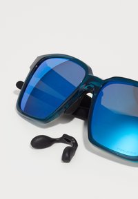 Gafas de sol cuadradas con montura de plástico en color turquesa y lentes espejados azules. Incluyen almohadillas de silicona negra para un ajuste seguro.