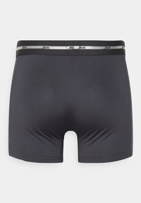 Mørkegrå bokser-shorts lavet af glat materiale. Har en ensfarvet farve, elastisk talje med et sølvlogo og en tætsiddende design.