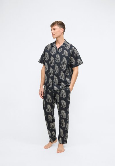 Schwarz gemusterter Schlafanzug mit einem kurzärmligen Hemd und lockeren Hosen, verziert mit großen Tiger-Motiven in Beige.