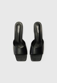 Schwarze Rutsch-Sandalen mit einem breiten, glatten Riemen oben, rechteckigem offenen Zehendesign und flacher Sohle. Texturierte Innenauskleidung.