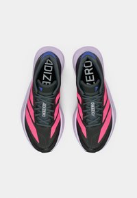 Paire de chaussures de course noires et roses avec des lacets gris et des semelles épaisses violet clair, vues de dessus sur un fond blanc.