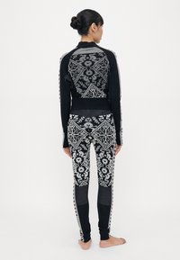 Zwarte gebreide sweater en legging met een geometrisch patroon in grijs. De sweater heeft een aansluitend ontwerp met geribbelde randen.