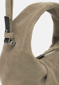 Borsa a spalla in suede color taupe con una forma curva e strutturata. Caratterizzata da una tracolla in pelle nera, una zip argentata e una texture morbida.