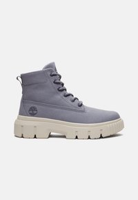 Botas de tobillo de lona gris con una suela blanca gruesa, que cuentan con un diseño de cordones y un logotipo de la marca en el costado. Superficie superior texturizada.