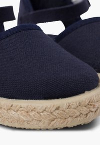 Espadrillas blu navy con tomaia in tessuto testurizzato, punta rotonda e suola avvolta in juta. Presentano un tacco piatto e cinturini regolabili.