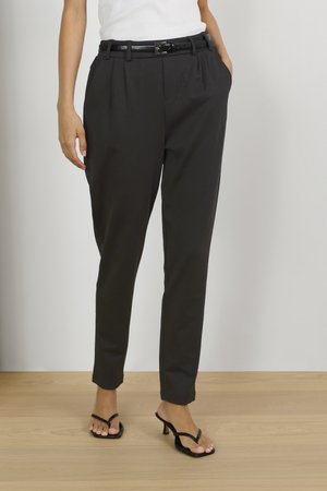 Pantaloni neri su misura con pieghe, dotati di una cintura nera lucida. Il tessuto ha una consistenza liscia e i pantaloni si restringono alla caviglia.