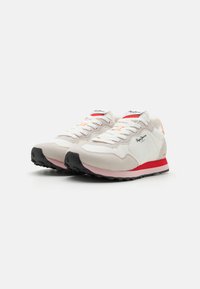 Hvide og lysegrå sneakers med ruskind og mesh-materialer, kontrasterende sort sål, røde og orange detaljer samt snørebåndsdesign.