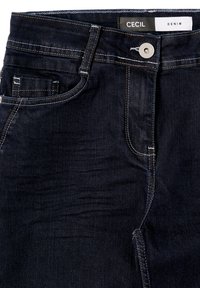 Donkerblauwe denim jeans met een gladde textuur. Kenmerken zijn onder andere contrasterende stiksels, meerdere zakken en een metalen knoopsluiting. Merklabel zichtbaar.