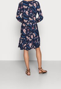 Robe à imprimé floral avec des manches longues, un ourlet volanté, fond navy avec des accents roses et bleus, fabriquée en matériau léger.