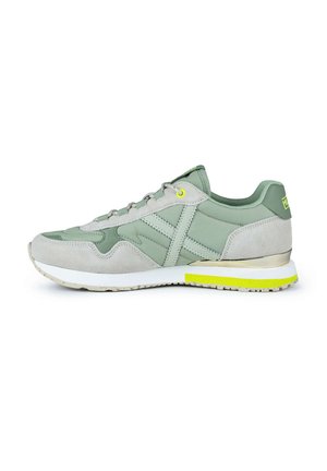 Zapatillas verdes con una mezcla de ante y materiales sintéticos, con una suela blanca, acentos amarillos y una lengüeta acolchada.