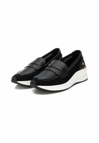 Zapatos negros sin cordones con parte delantera de cuero texturizado y lados de malla, que presentan una suela de cuña blanca y un pequeño acento de logo metálico.