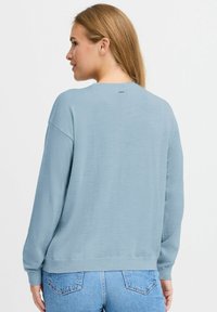 Ljusblå sweatshirt med rund halsringning, långa ärmar och avslappnad passform. Slät textur med ribbat avslut och cuffar.