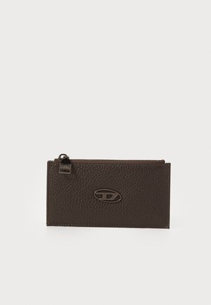 Portefeuille en cuir marron avec une texture granuleuse, une fermeture zippée et un accent logo ovale en finition métallique.
