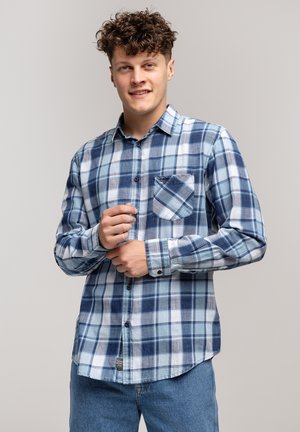 Niebieska i biała koszula w kratę z długimi rękawami, zapinana na guziki, z kieszenią na piersi. Wykonana z tkaniny o miękkiej fakturze. Luźny krój.