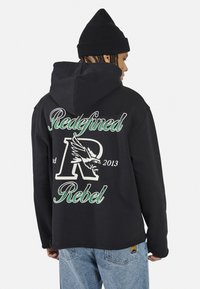Fekete kapucnis pulóver, zöld és fehér "Redefined Rebel" felirattal, sas mintázattal és a "2013" évszámmal a hátán.